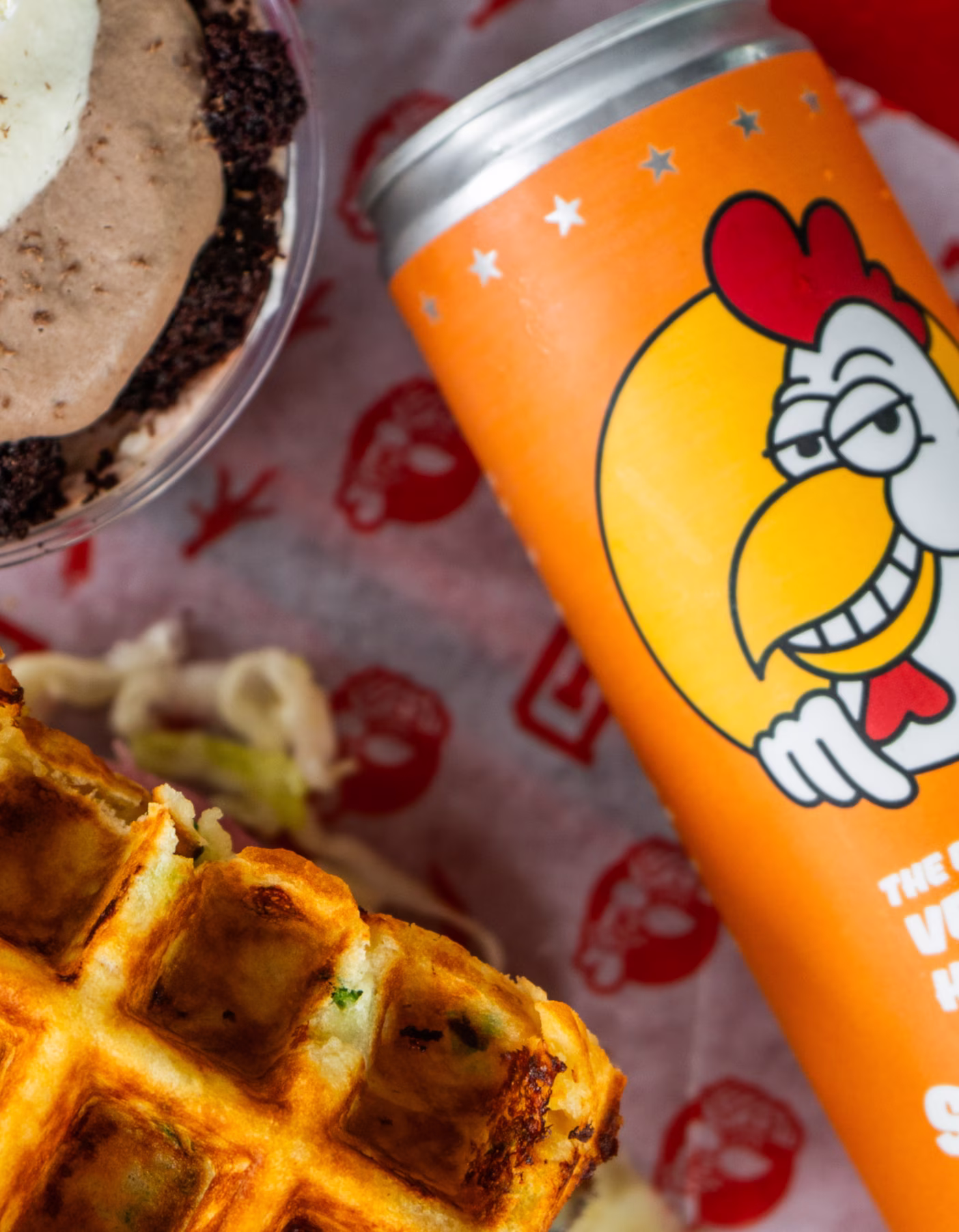 A fried chicken sandwhich with waffles, a can of sweet tea, and a chocolate cake